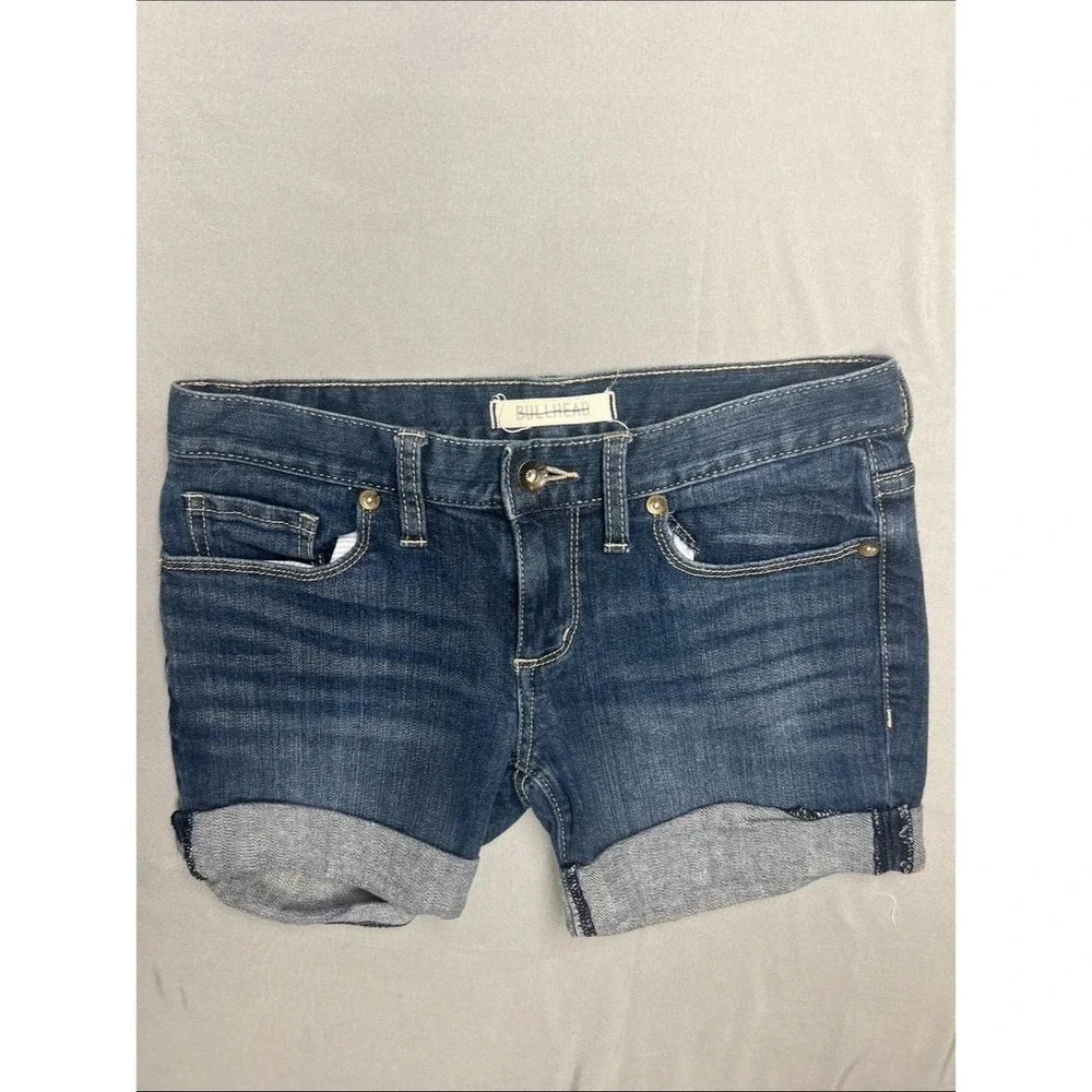 Bullhead denim shorts in a mid to dark blue wash. Rolled hem with cuffed